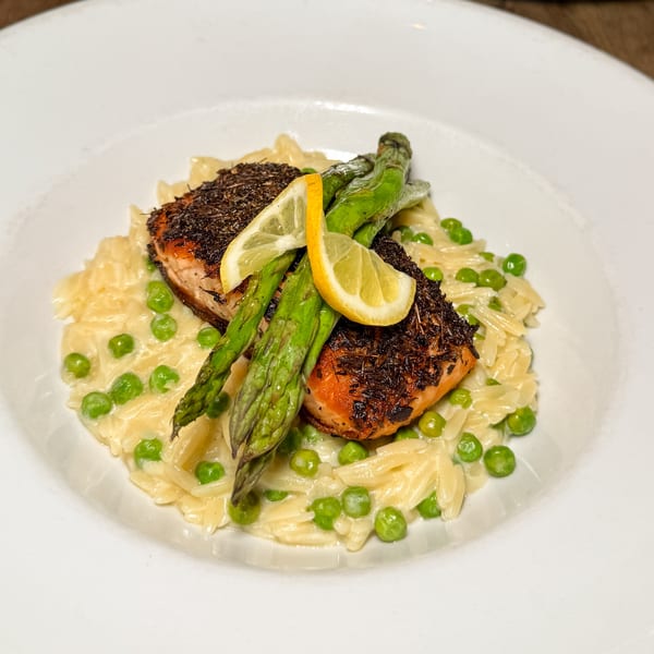 Pan-seared salmon with asparagus, lemon slices, and orzo pasta with green peas.
